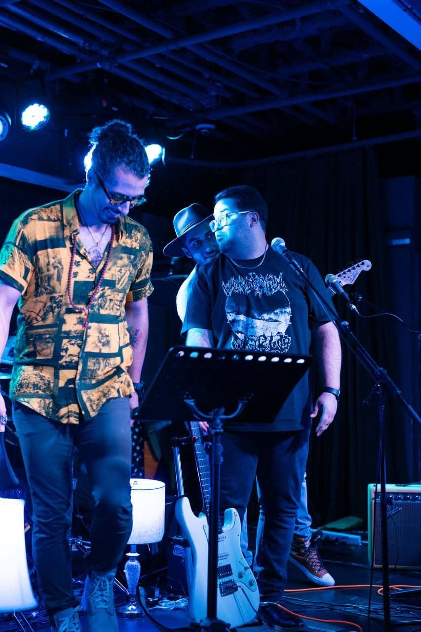 Arash, Matin and Pouyan performing live at Drake Underground under blue stage lights.