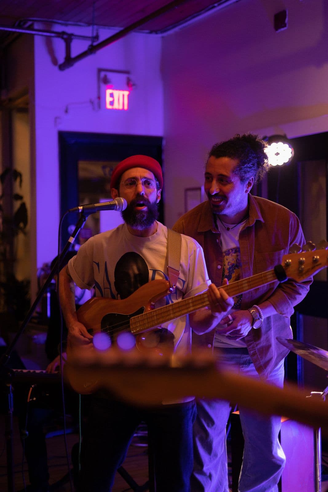 Matin and guest bassist Maziar sharing the stage at a Beytooteh show under soft purple lighting, creating a lively, friendly atmosphere.